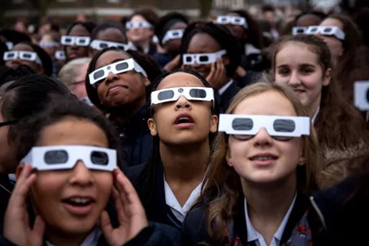 Students wear eclipse glasses at the Royal Observatory Greenwich during the 2015 solar eclipse in London, England. Only those who are in the path of totality can remove protective eyewear during the short period in which the moon completely blocks the sun. (Rob Stothard/Getty Images)