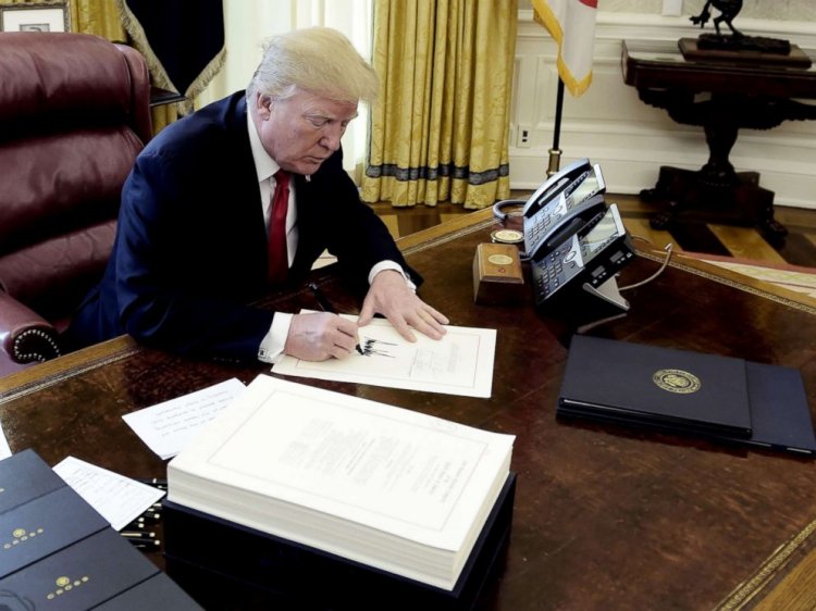 President Donald J. Trump signs a document during an event to sign the Tax Cut and Reform Bill in the Oval Office at The White House, Dec. 22, 2017.