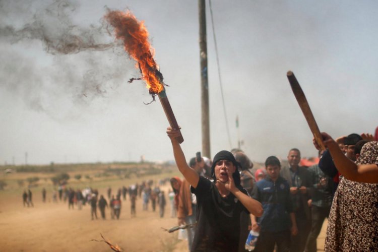 A Palestinian demonstrator shouts after burning a representation of an Israeli flag during a protest where Palestinians demand the right to return to their homeland, at the Israel-Gaza border, east of Gaza City, April 13, 2018. REUTERS/Mohammed Salem