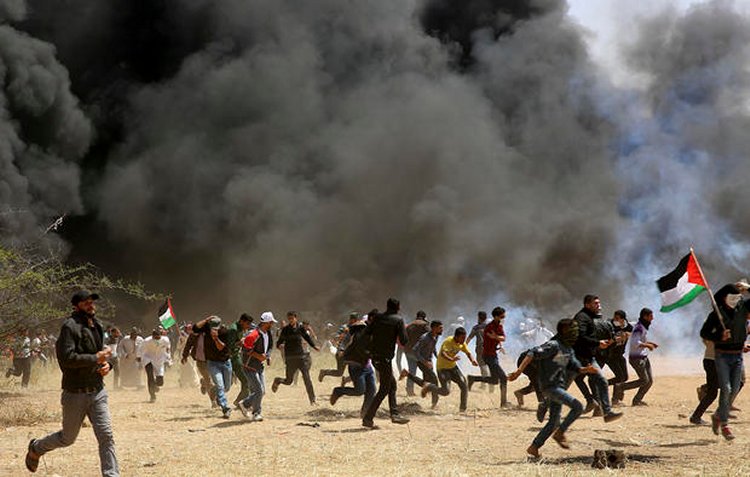 Palestinian protesters run to cover from teargas fired by Israeli soldiers during clashes with Israeli troops along Gaza's border with Israel, east of Khan Younis, Gaza Strip, Friday, April 6, 2018. ADEL HANA / AP